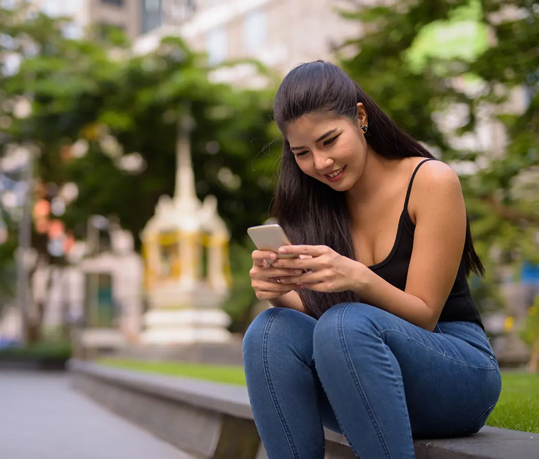 Filipina woman using a dating app outdoors looking for a serious relationship