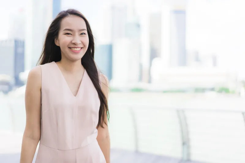 Smiling Filipina woman in urban setting, embodying warmth and emotional presence