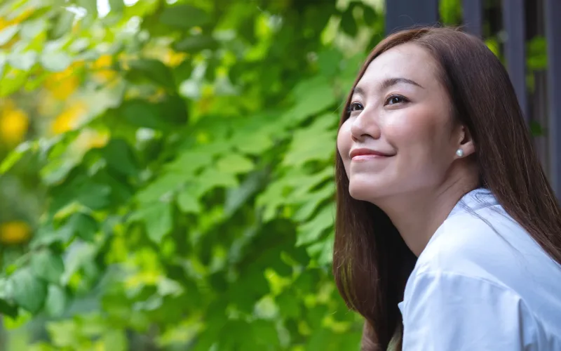 Filipina smiling peacefully in garden, reflecting thoughtful approach to courtship and family values