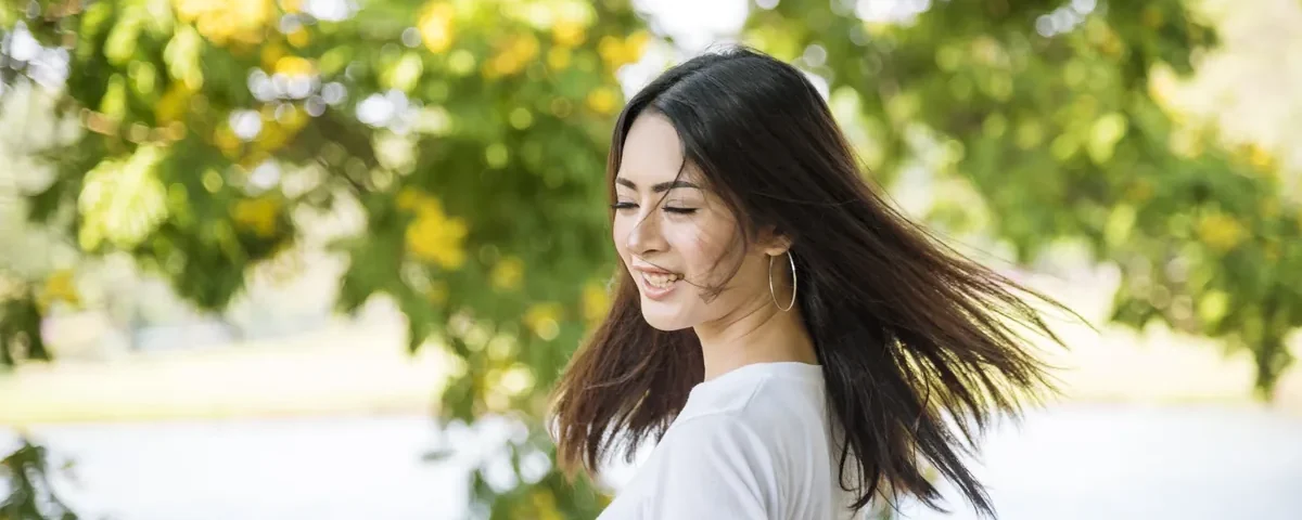 Woman smiling at her phone while relaxing in a park setting