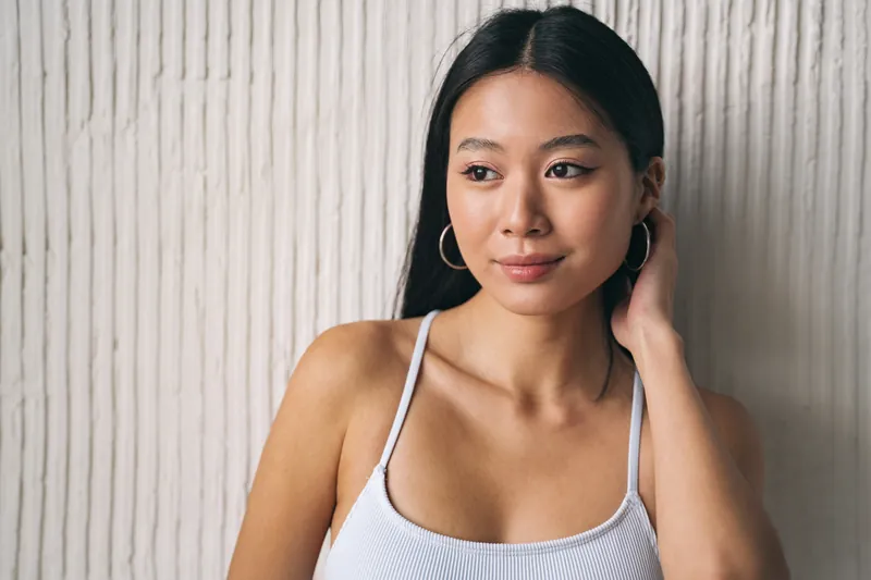 Woman with confident expression and decorative earrings looking directly at camera
