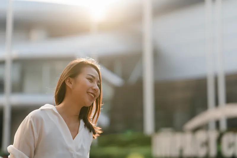 Woman outdoors with coffee cup looking thoughtful on a sunny day