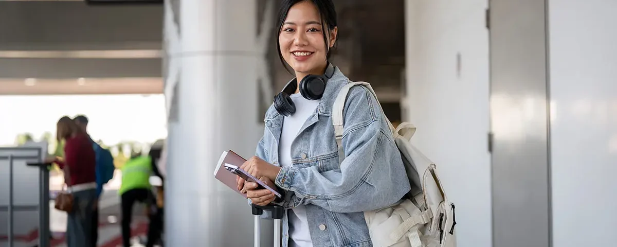 Filipina woman at airport smiling while preparing for travel to meet her partner in the USA