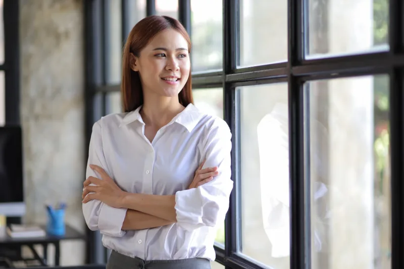 Professional Filipina woman by window in modern office, composed and confident