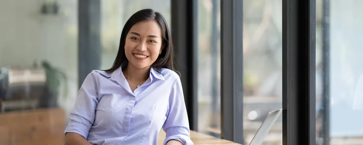 Woman smiling while working on laptop in office environment during Filipina chat online