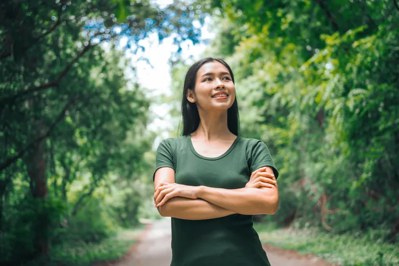 Woman standing happily in tropical green forest landscape