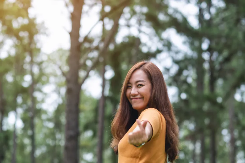 Filipina woman smiling while making heart gesture in park