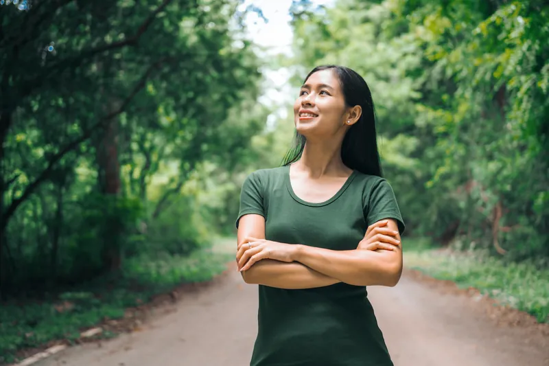 Filipina woman standing happily with natural green park background