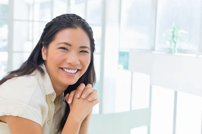 Woman smiling warmly while looking directly at camera indoors