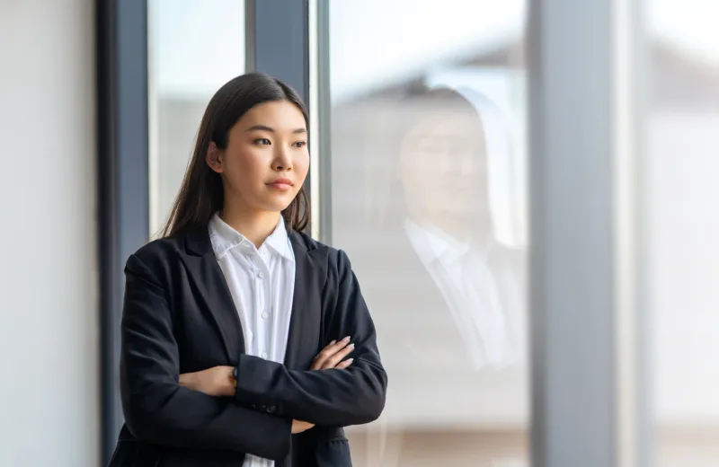 Professional woman by window with composed demeanor, suggesting serious commitment and intentional planning