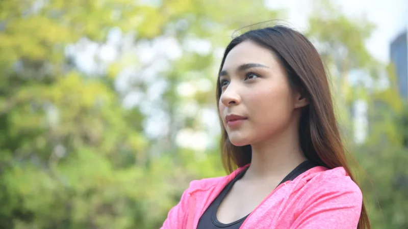 Woman with thoughtful expression outdoors, representing the trust-building process in long-distance relationships
