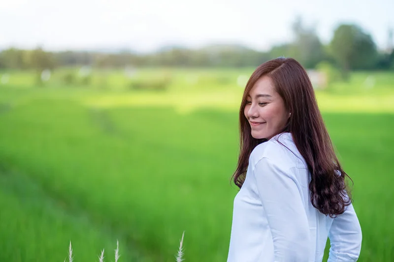Filipina smiling in park setting demonstrating open body language and non-verbal communication