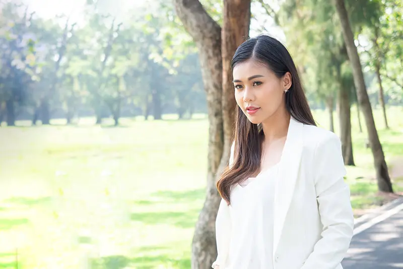 Woman in outdoor park setting with contemplative expression reflecting Filipino family values