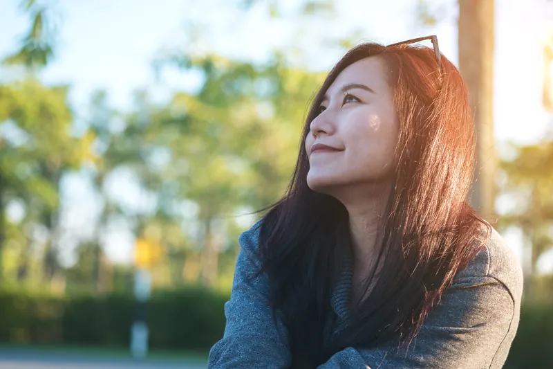 Woman in park with thoughtful expression, reflecting on genuine connection