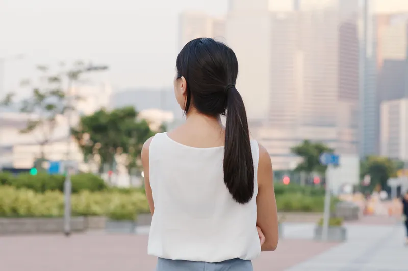 Filipina woman with contemplative gaze in city, reflecting genuine thoughts