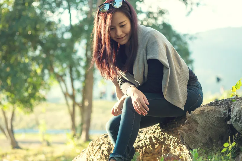 Woman sitting in park with genuine, candid smile expressing natural warmth
