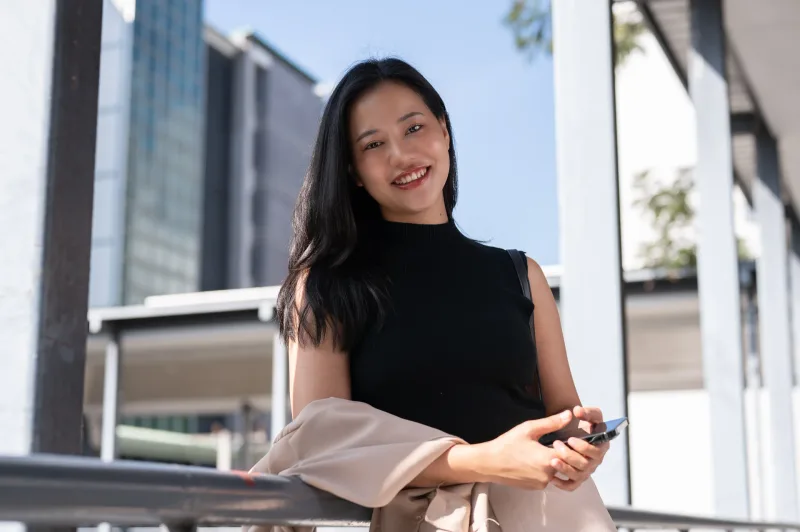 Woman engaged with smartphone in urban setting, representing modern communication in the transition from online to offline dating.