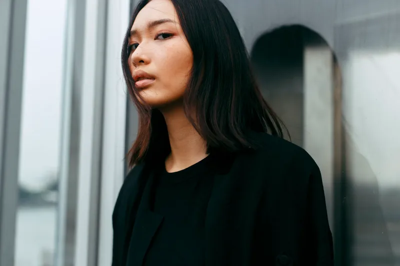 Woman with composed, introspective gaze outdoors, reflecting the cultural values and thoughtfulness in Asian dating courtship.
