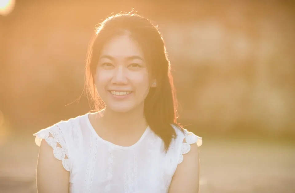 Asian woman smiling in golden hour light with genuine warmth