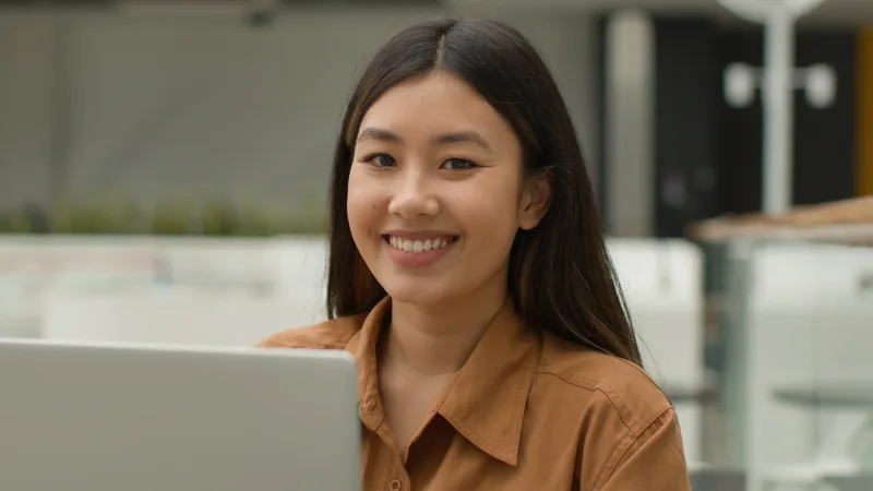Happy Asian woman in casual outdoor setting with genuine smile