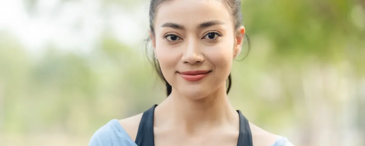 Woman smiling confidently outdoors in blue clothing with natural light