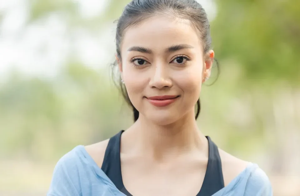 Woman smiling confidently outdoors in blue clothing with natural light