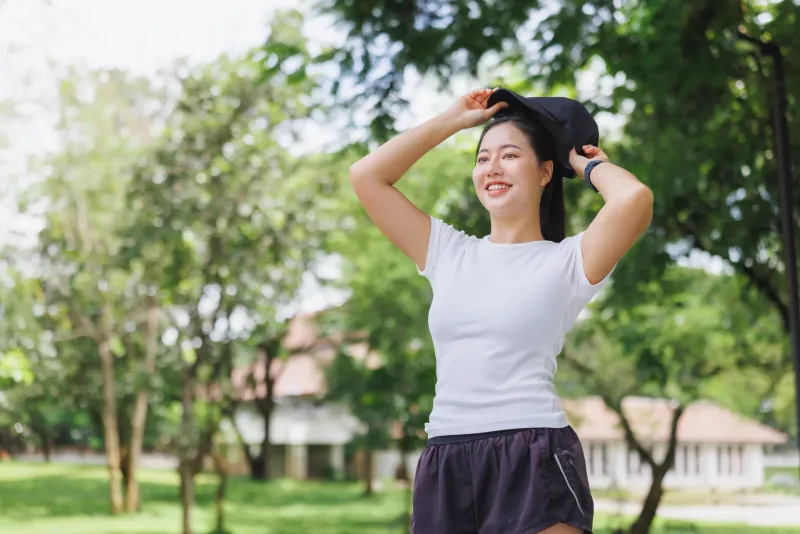 Woman smiling in park setting with greenery background