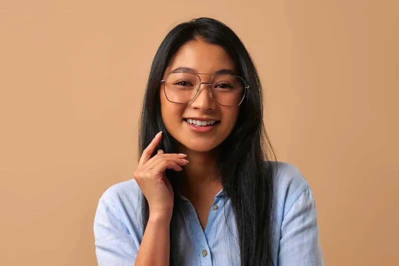 Woman with glasses smiling confidently in studio setting, example of a complete dating profile photo