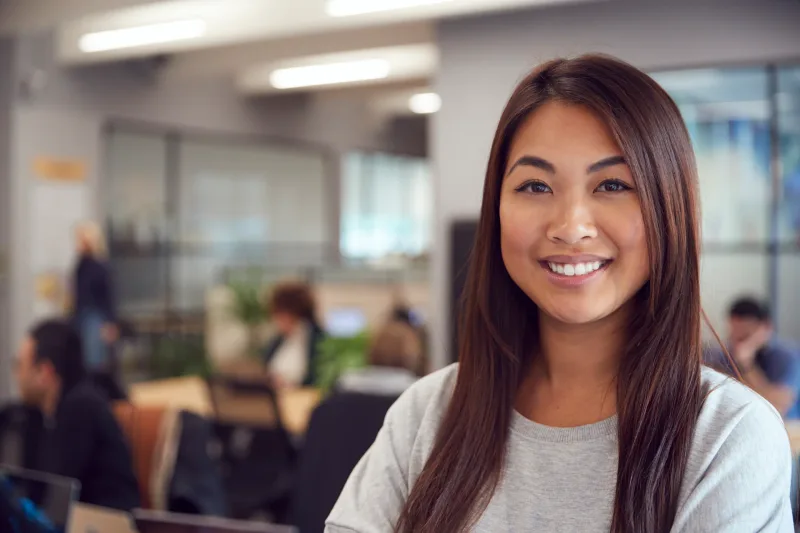 Professional Asian woman with warm, genuine smile in office setting
