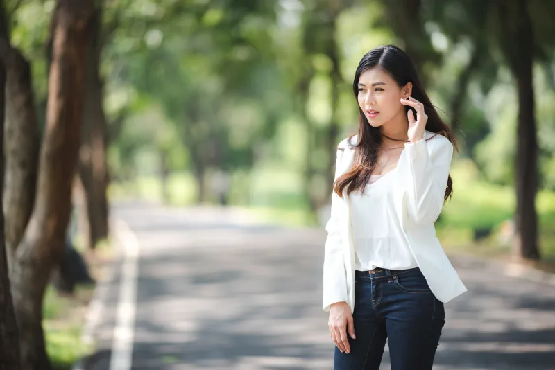 Woman in casual outdoor setting with phone, daytime park environment