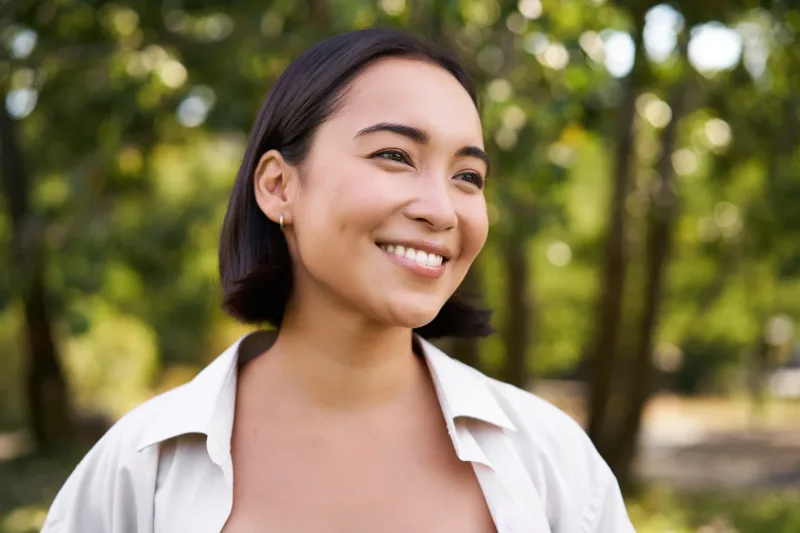 Smiling woman in natural outdoor light, cheerful expression