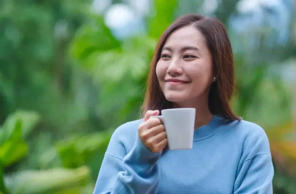 Woman enjoying coffee outdoors with serene expression