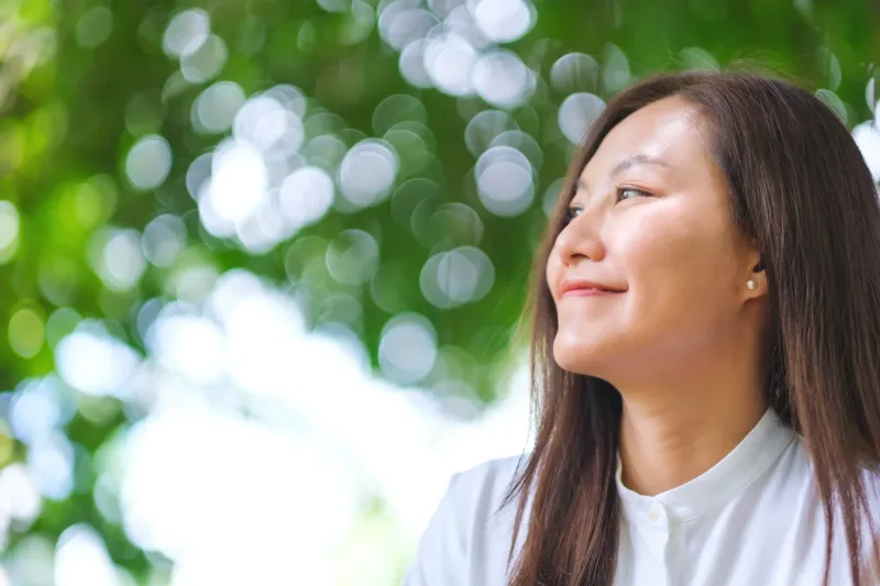 Young woman relaxing peacefully in garden with natural bokeh