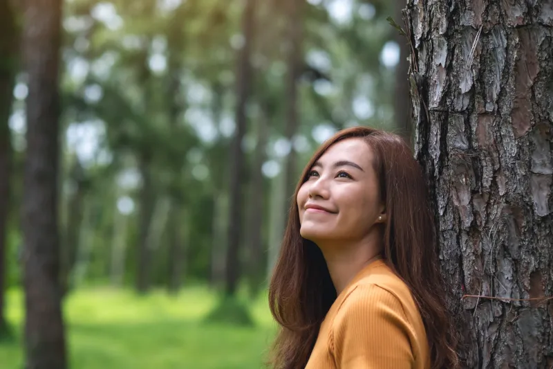 Asian woman in forest setting with contemplative expression