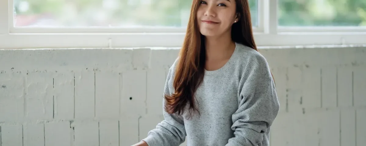 Asian woman with contemplative smile in natural window light