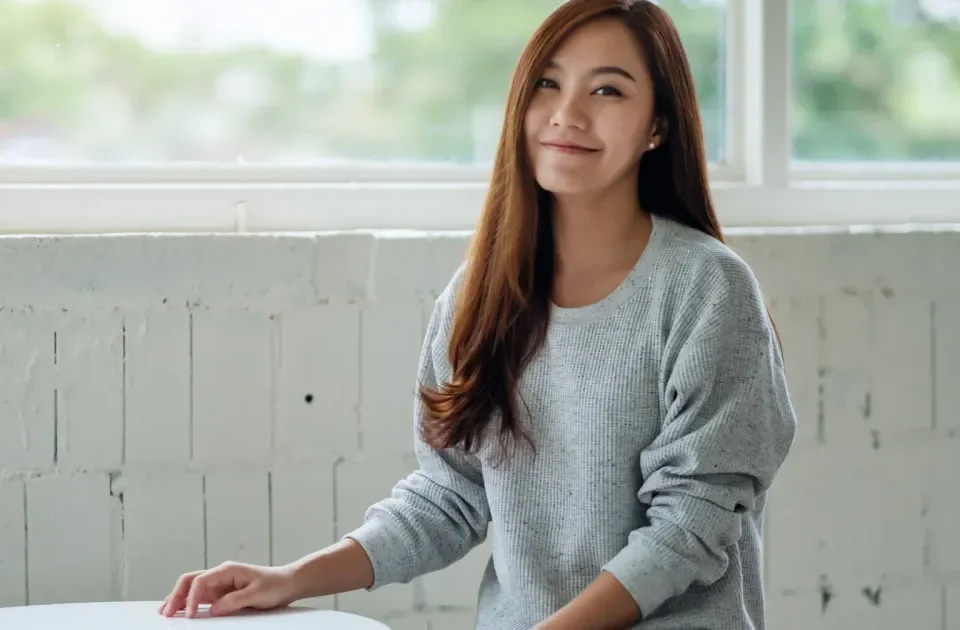 Asian woman with contemplative smile in natural window light