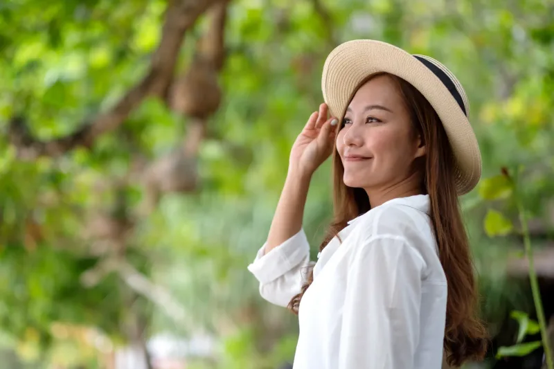 Woman in straw hat with peaceful expression in natural outdoor setting