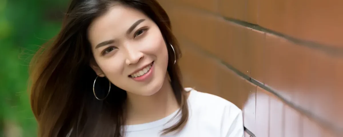 Confident Asian woman smiling outdoors in casual attire