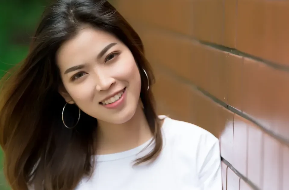 Confident Asian woman smiling outdoors in casual attire