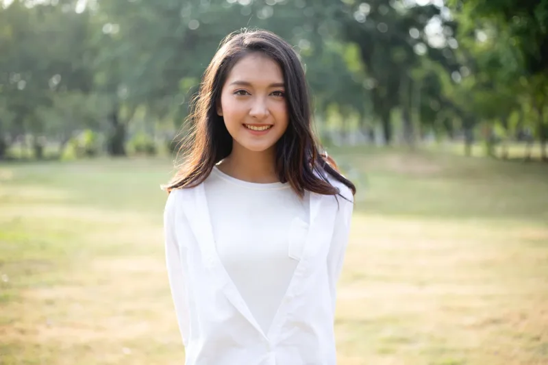 Asian woman with warm smile in golden hour park setting