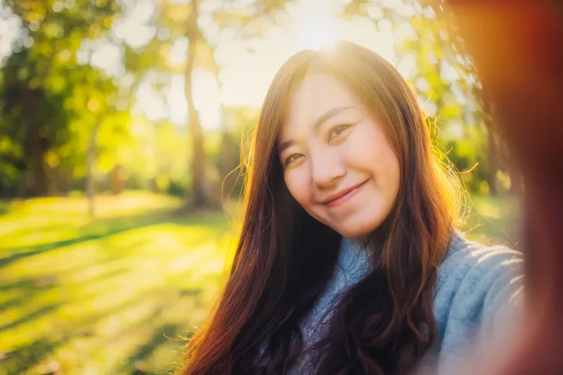 Beautiful Asian woman smiling outdoors in peaceful natural setting