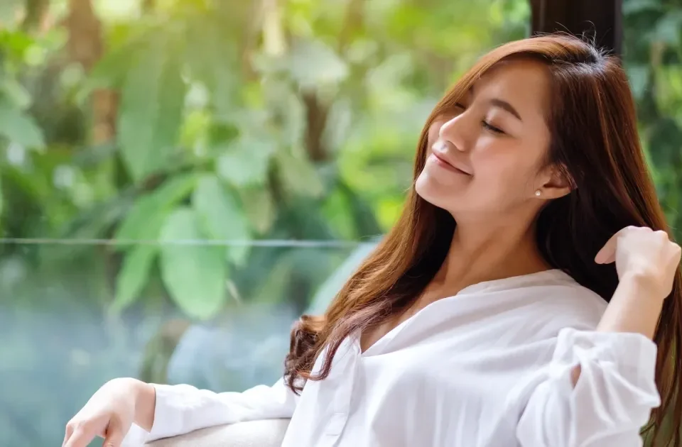 Asian woman sitting peacefully in nature, thoughtful expression