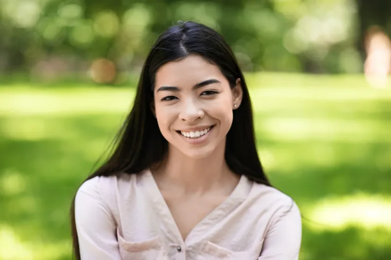 Smiling Asian woman in outdoor natural light, approachable expression