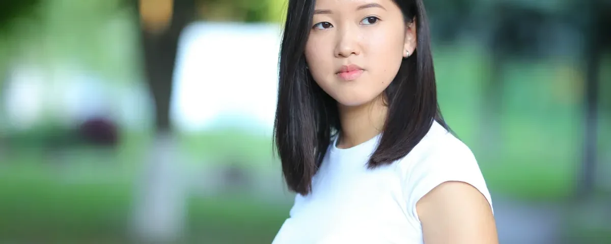 Woman with black bob hair looking thoughtfully outdoors in natural light