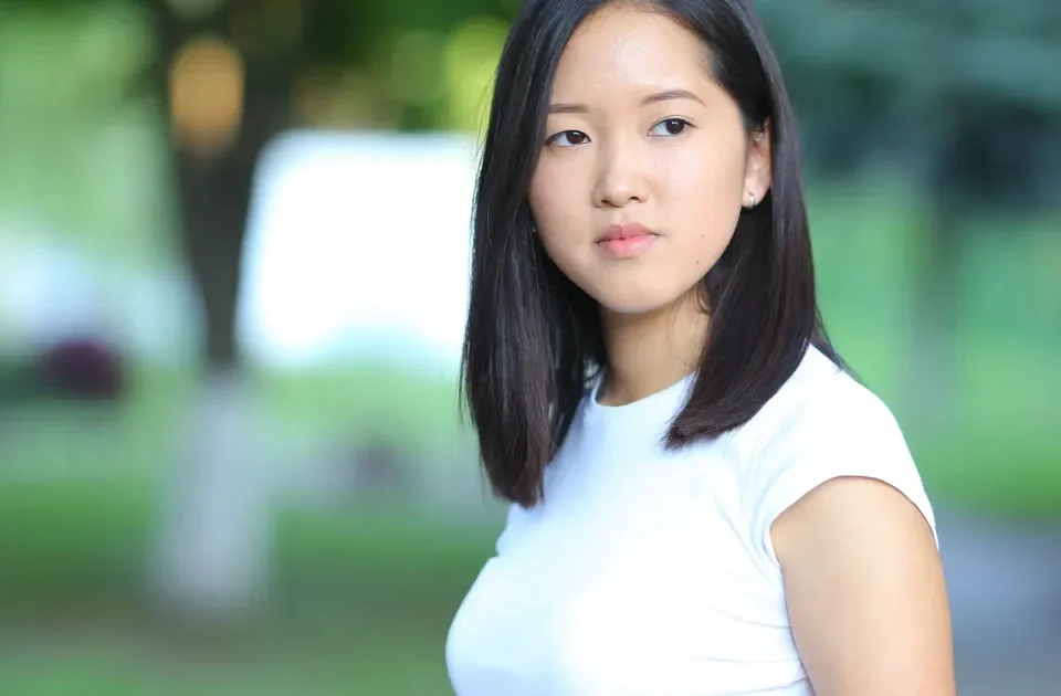 Woman with black bob hair looking thoughtfully outdoors in natural light