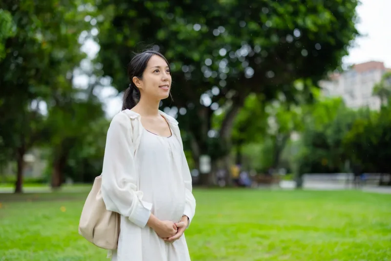 Woman relaxing in green park setting with serene, contemplative demeanor