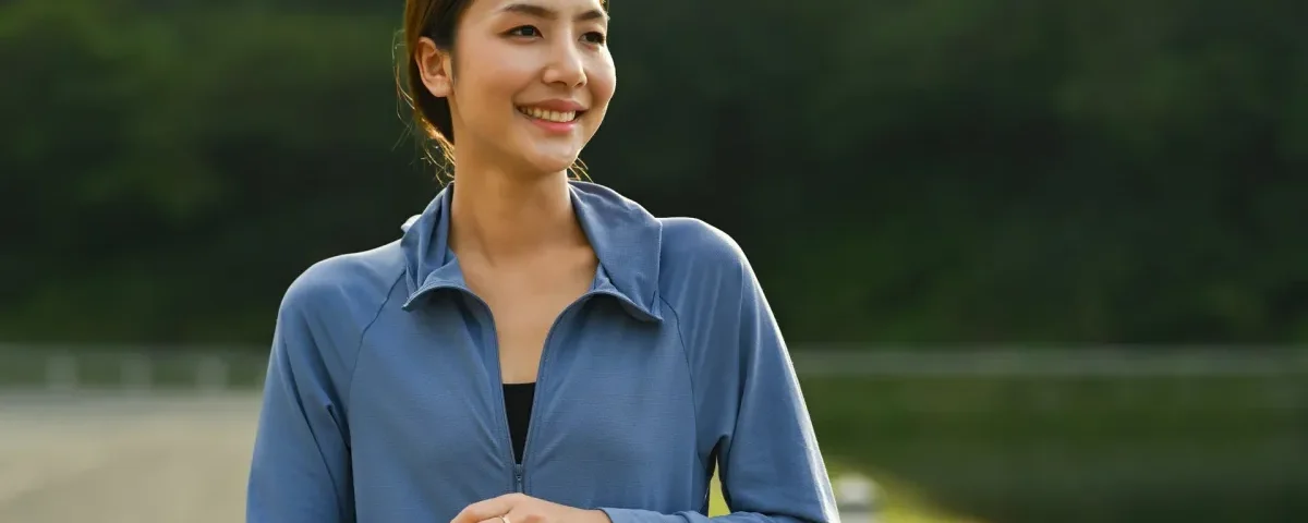 Asian woman smiling outdoors with smartphone, representing connection and modern dating platforms