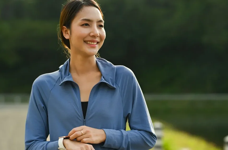 Asian woman smiling outdoors with smartphone, representing connection and modern dating platforms