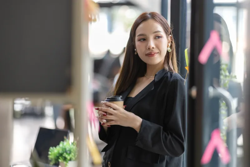 Confident Asian woman with coffee in urban setting, embodying intentional dating approach