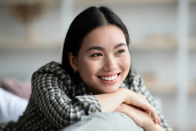 Woman relaxing on sofa with relaxed, happy expression